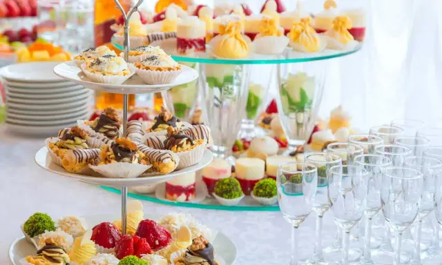 Un buffet de hors d'œuvre varié avec des mini-tartes, des éclairs au chocolat et des fruits frais, prêt à ravir les invités.