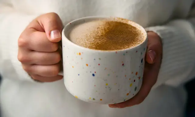Ciepły napój w kolorowym kubku, posypany cynamonem. Czy to chai latte? Idealny na chłodne dni.