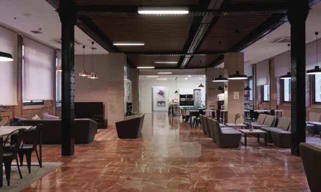 Amplio salón con suelo de mármol rojo, sofás, mesas y una mesa de billar. La **residencia diagonal** ofrece un espacio moderno y acogedor.