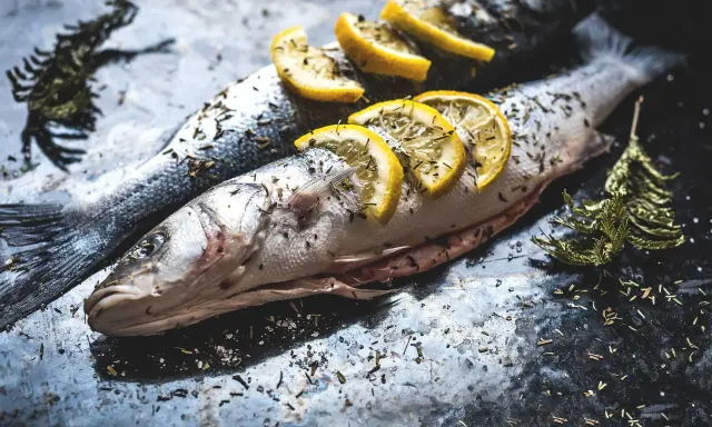 Deux poissons entiers, assaisonnés d'herbes et garnis de rondelles de citron, prêts pour un quel poisson barbecue.