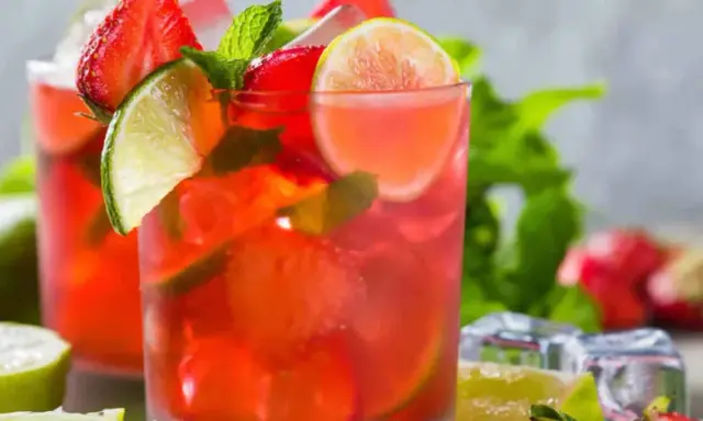 Två glas med en uppfriskande strawberry mojito, garnerade med jordgubbar, lime och mynta. Perfekt för en varm sommardag.