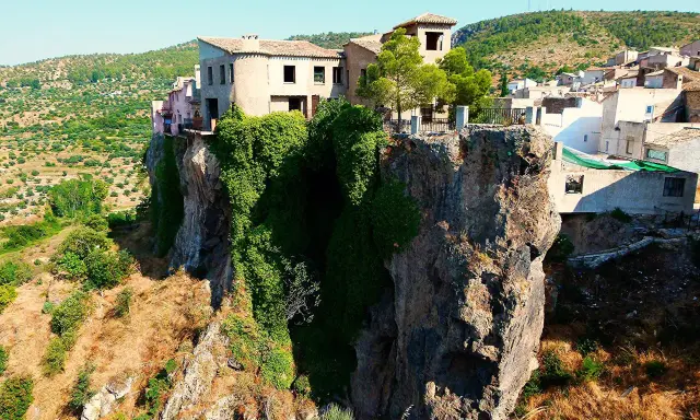 Casas aferradas a un acantilado, con vegetación cubriendo la roca. El mirador de la Molatica ofrece vistas espectaculares del paisaje.