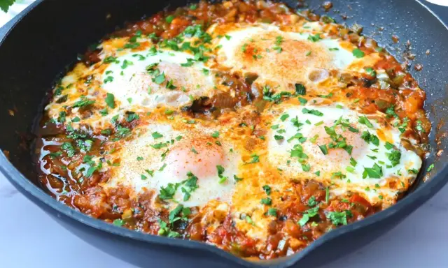 Huevos pochados en salsa de tomate y pimientos, un plato perfecto para tus recetas con huevos. Espolvoreado con perejil fresco.