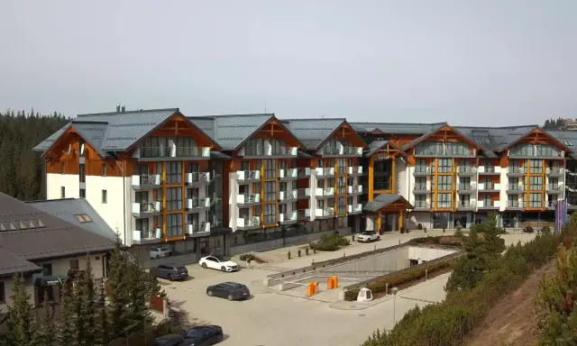 Widok z kamer w Bukowinie Tatrzańskiej na nowoczesny hotel z drewnianymi elementami i parkingiem.