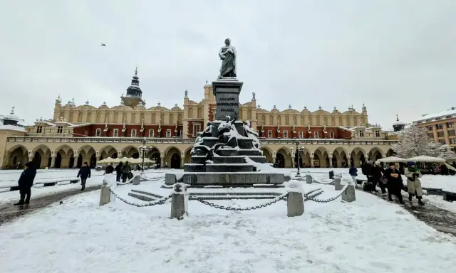 Zimowy weekend w Krakowie. Rynek Główny ze Sukiennicami i pomnikiem Adama Mickiewicza, pokryty śniegiem.