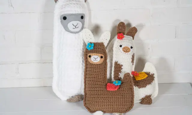 Un grupo de adorables llamas amigurumi, hechas a mano con lana, posan juntas.
