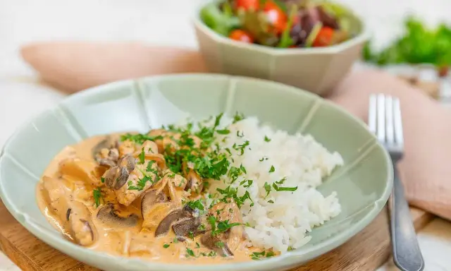 En krämig kyckling stroganoff med champinjoner och ris, toppad med persilja. En härlig middag!