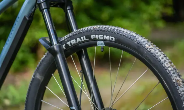 Opona rowerowa "Trail Fiend" z widocznym bieżnikiem, zwijana, gotowa na terenowe wyzwania.