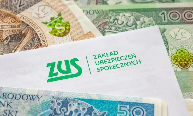 Koperta z logo ZUS leży na stosie polskich banknotów. z15b druk.