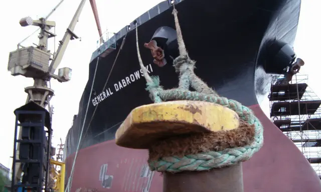 Gros plan sur une aussière, définition de l'amarrage d'un navire, le "GENERAL DABROWSKI", au port. Grues et échafaudages en arrière-plan.