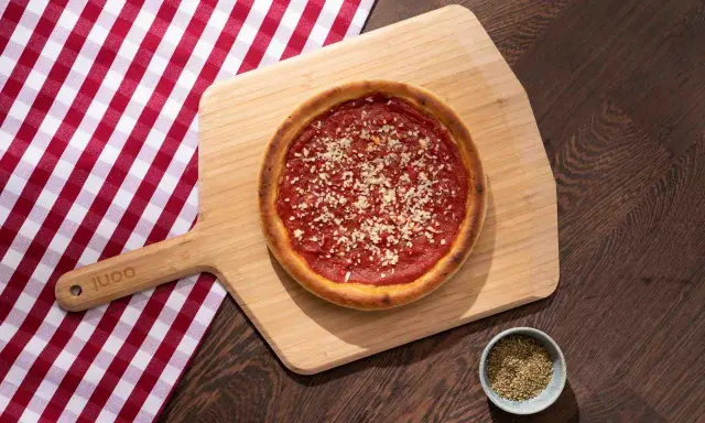 Pizza sur planche en bois, avec une nappe à carreaux rouges et blancs. La proportion levain farine eau est parfaite pour cette croûte dorée.