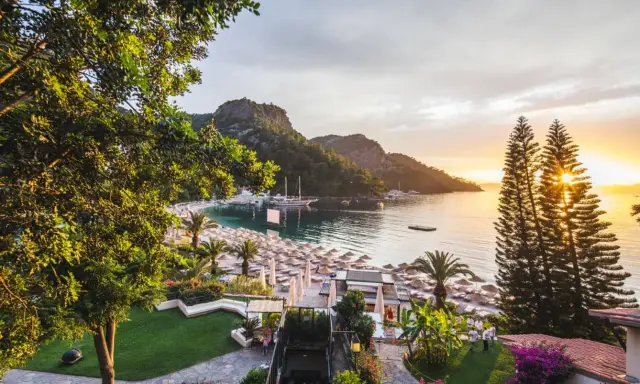 Malownicza zatoka z łodziami, plaża z leżakami i palmami, a na zboczu wzgórza wspaniały hillside beach club.