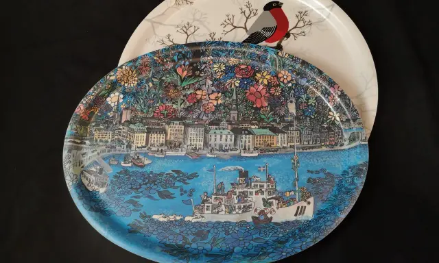 Två brickor, en med en detaljerad stadsvy och fartyg, den andra med en domherre och träd. En fin bengt elde bricka.