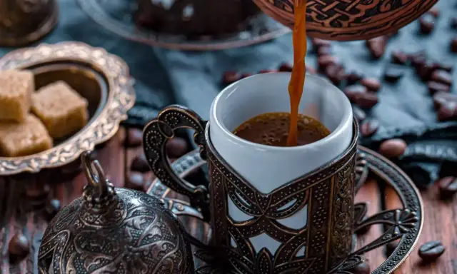 Heißer Mokka wird in eine verzierte Tasse gegossen. Der Unterschied zwischen Mokka und Espresso liegt in der Zubereitung und Intensität.