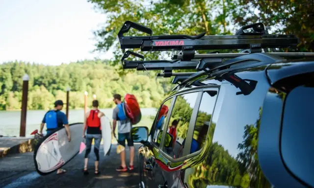 Ludzie przygotowują się do wodnej przygody, transport kajaka i desek SUP do jeziora.