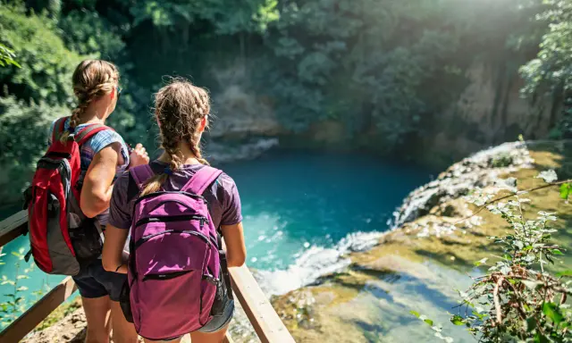 Due ragazze con zaini ammirano una cascata durante un trekking in Toscana montagna.