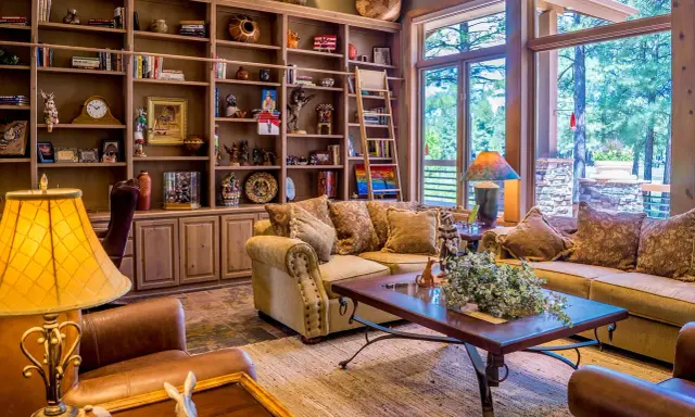 Accogliente soggiorno con libreria in legno, divani imbottiti e un tavolino, perfetto per un arredamento casa campagna.