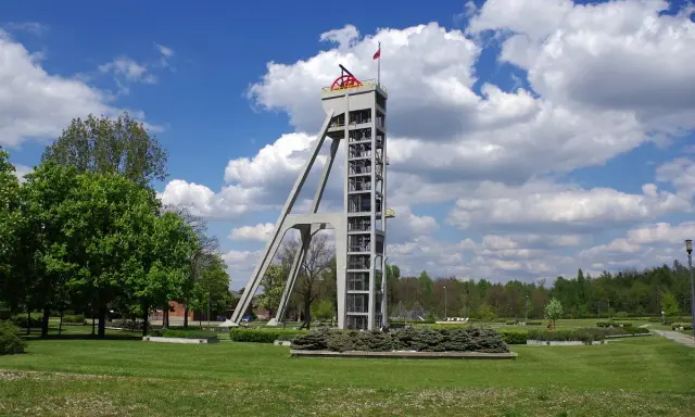 Betonowy szyb górniczy, dawniej szyb prezydent, góruje nad zielonym parkiem.