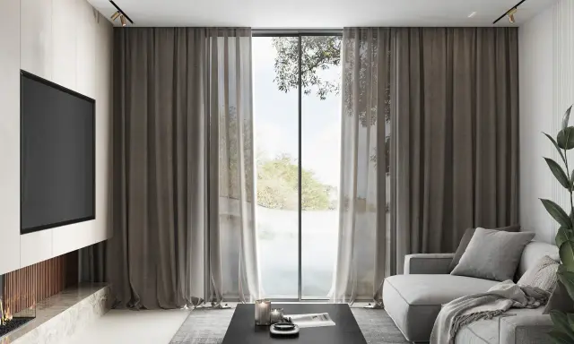 Elegante salón con chimenea, sofá gris y una ventana con cortinas que permiten combinar estores y cortinas para un ambiente acogedor.