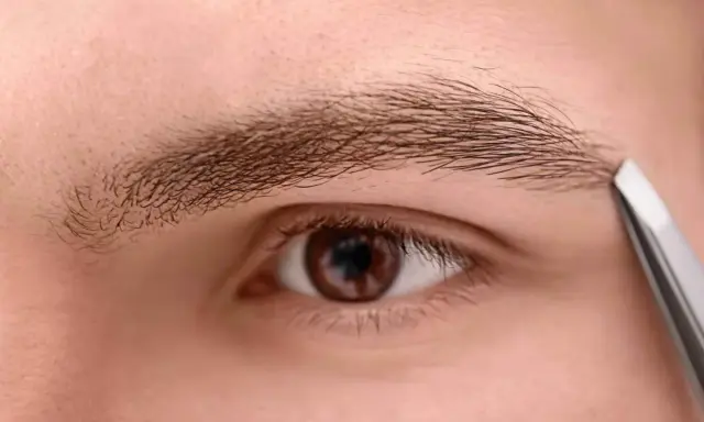 Un homme utilise une pince à épiler pour tailler un sourcil qui rebique, affinant son regard.
