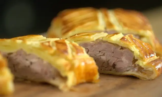 Tranche d'un plat lorrain, une viande savoureuse enveloppée dans une pâte feuilletée dorée.