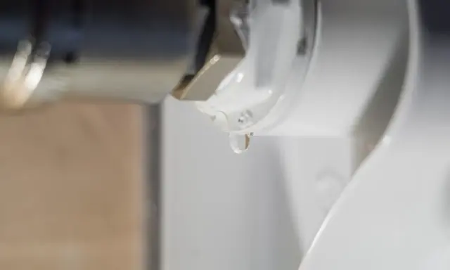 Una gota de agua cae de la rosca de un radiador. El radiador pierde agua por la rosca, indicando una posible fuga.