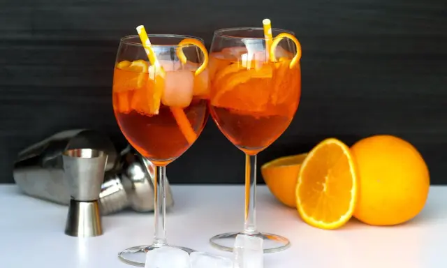 Deux Aperol Spritz prêts à déguster, avec des oranges fraîches et des glaçons. La recette parfaite pour un apéritif ensoleillé.