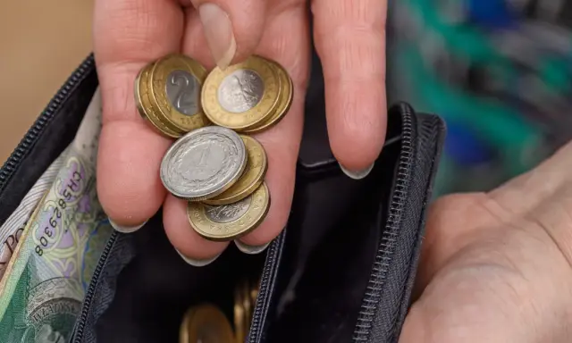 Dłoń z monetami i banknotami w portfelu. Czy to wystarczy na emeryturę po 40 latach pracy? Kalkulator emerytalny pomoże to sprawdzić.