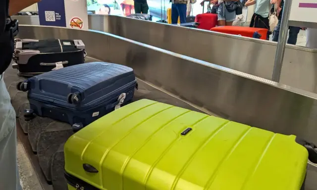 Walizki na taśmie bagażowej. Zastanawiasz się, co zabrać na wakacje all inclusive? Oto inspiracja!
