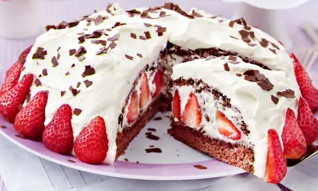Saftige Stracciatella Torte mit frischen Erdbeeren und Schokostückchen, üppig mit Sahne verziert.