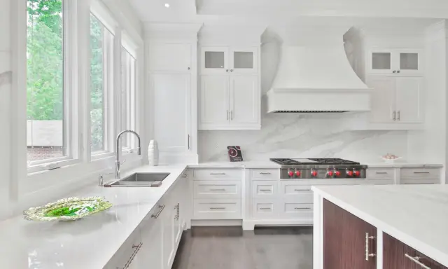 Cocina moderna y luminosa con muebles blancos, encimeras de cuarzo y electrodomésticos de acero inoxidable. Perfecta para pintar muebles de cocina y darles un nuevo aire.