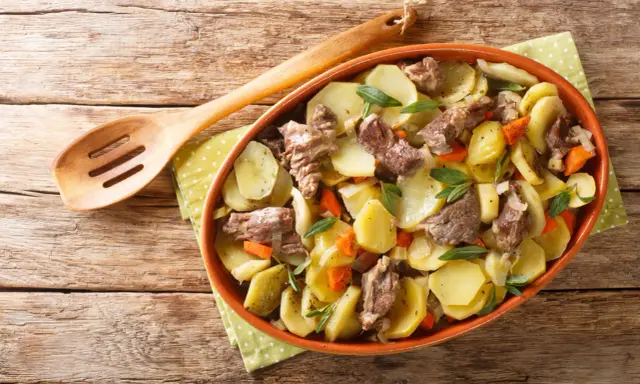 Un plat de pommes de terre et de viande mijotée, garni d'herbes fraîches, une spécialité alsace réconfortante.