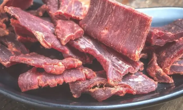 Suszone plastry wołowiny na czarnym talerzu. Idealne do przekąski, gdy szukasz prostego beef jerky przepis.