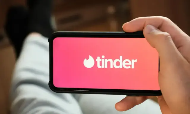 Dłoń trzyma smartfon z logo popularnych portali randkowych Tinder.