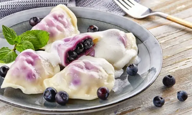 Pyszne pierogi z jagodami, polane śmietaną, z miętą i świeżymi owocami. Idealny przepis na lato!