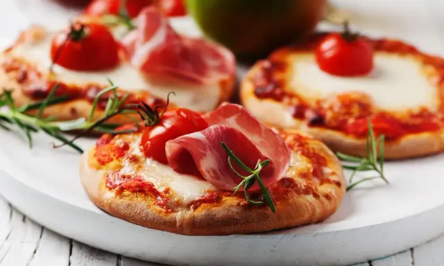 Pizzerinki z serka wiejskiego, pomidorkami koktajlowymi i szynką parmeńską, ozdobione rozmarynem.