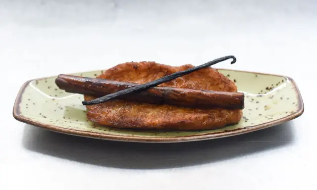 Torrijas de leche y canela, doradas y crujientes, con una rama de canela y vainilla. ¡Perfectas para aprender como hacer torrijas de leche y canela!