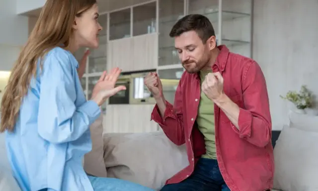 Coppia in conflitto, lei gesticola con rabbia, lui stringe i pugni. Una scena che illustra le difficoltà nel come convivere con un narcisista.