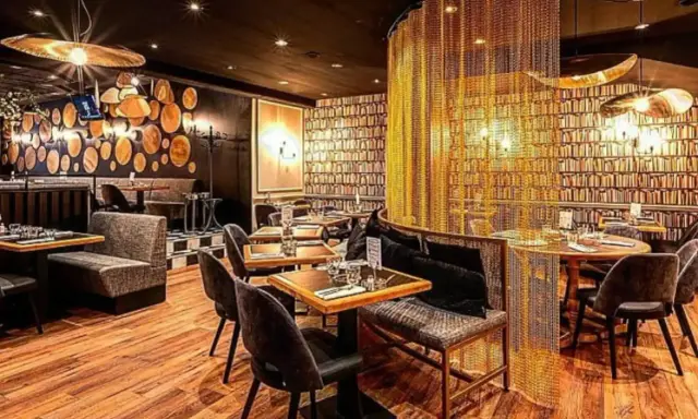 Intérieur chic du restaurant Letz, avec des tables dressées, des banquettes confortables et un rideau de chaînes dorées.