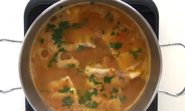 Guiso de corvina burbujeante con perejil picado, listo para servir. ¡Perfecto para tus recetas de corvina guisada!