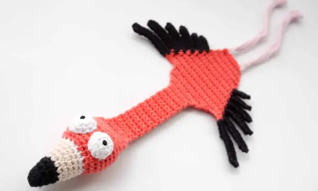 Flamenco amigurumi hecho a mano, con ojos saltones y pico bicolor. ¡Un patrón gratis para crear tu propio flamenco!