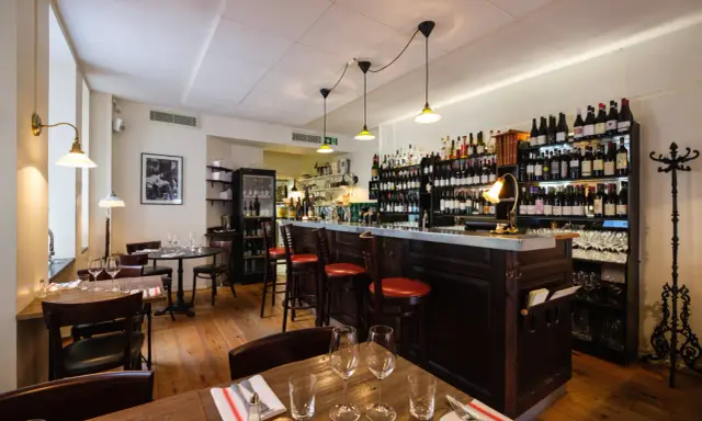 Mysig vinbar med trägolv, bardisk och hyllor fyllda med flaskor. Perfekt för att läsa bouchon recensioner över ett glas vin.