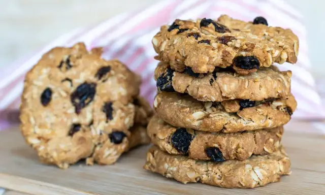 Una pila di biscotti integrali con uvetta e mandorle, perfetti biscotti senza zucchero per una pausa sana.