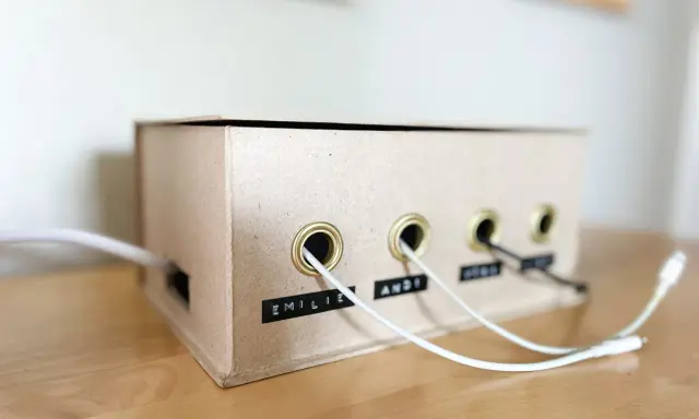 Kreative ladekabel aufbewahrung selber machen aus einem Karton. Kabel sind ordentlich durch Ösen geführt und beschriftet.