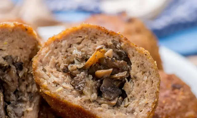 Kotlety mielone z pieczarkami, jeden przekrojony, ukazujący soczyste nadzienie.