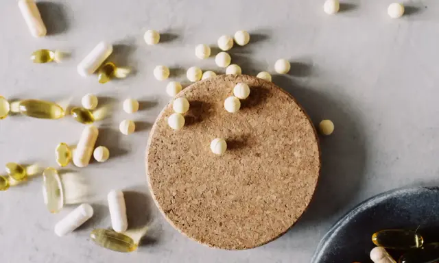 Kapseln und Pillen, darunter auch solche, die bei **Magnesium zum Abnehmen** helfen könnten, liegen verstreut auf hellem Untergrund.