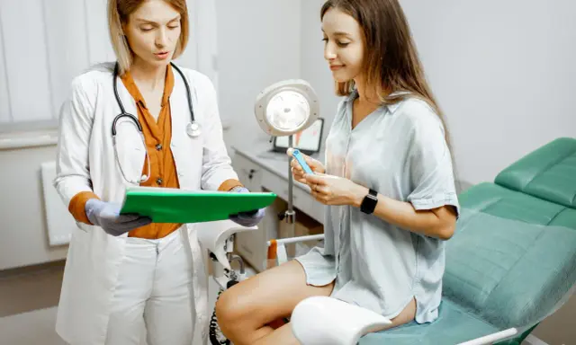 Lekarka wyjaśnia pacjentce, czym jest cytologia, pokazując jej przyrząd do badania.