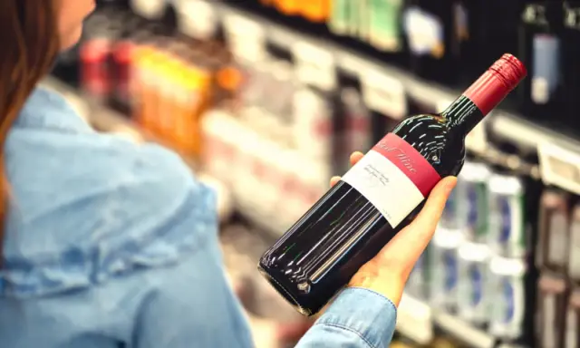 Kobieta wybiera wino, zastanawiając się, czy to jej osobisty wysokofunkcjonujący alkoholik test.