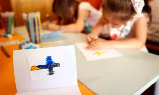 Dzieci rysują krzyże, ucząc się o religii w szkole. Na pierwszym planie symbol wiary.