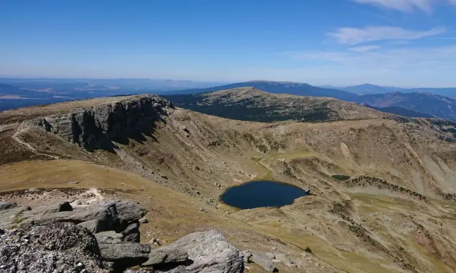 Paisaje montañoso con un lago azul en un valle, ideal para senderismo Soria.